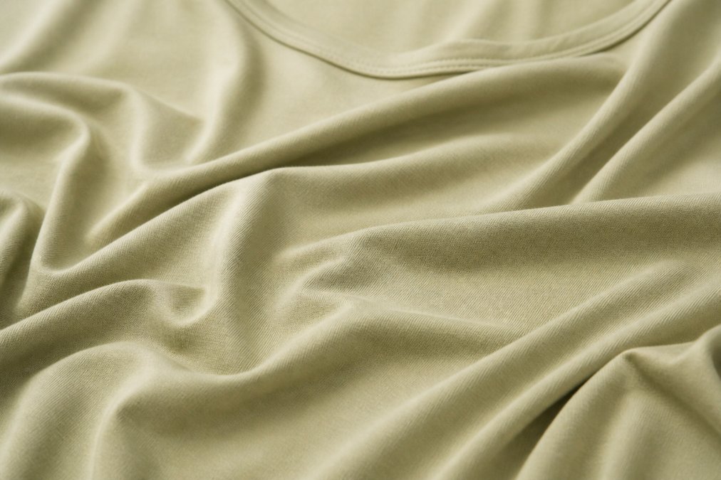 Close-up of modal fabric draped elegantly showing smooth texture and natural sheen, with soft natural lighting highlighting the fabric's lustrous surface and fluid drape quality