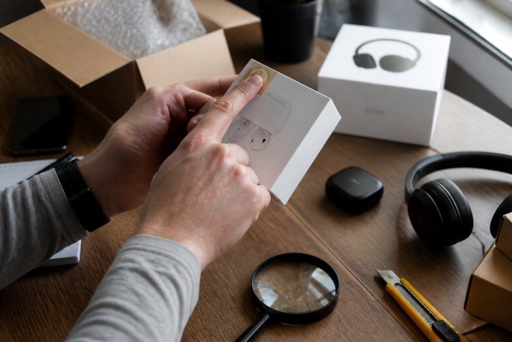Close-up of hands examining product packaging and checking authenticity labels on electronics