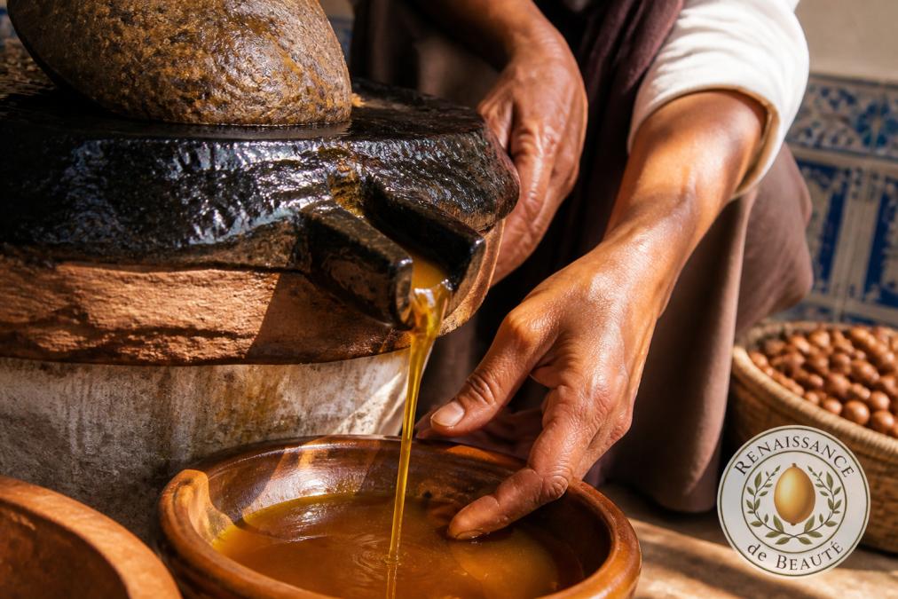 Close-up of freshly extracted golden argan oil dripping slowly from traditional stone press equipment, with hands visible guiding the process in warm natural lighting