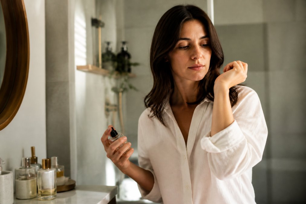 Woman applying perfume to her wrist while considering how skin chemistry affects the scent.