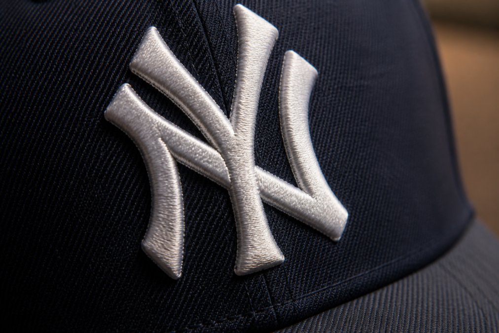 Close-up of a sports cap showing detailed embroidery stitching on the front logo with sharp thread definition and tight stitch density against the fabric, professional lighting highlighting the craftsmanship