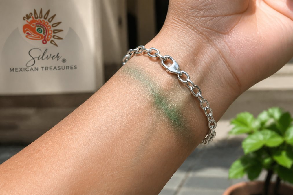 Close-up of a wrist wearing a sterling silver bracelet, showing slight green discoloration on the skin beneath the bracelet, with natural daylight illuminating the affected area