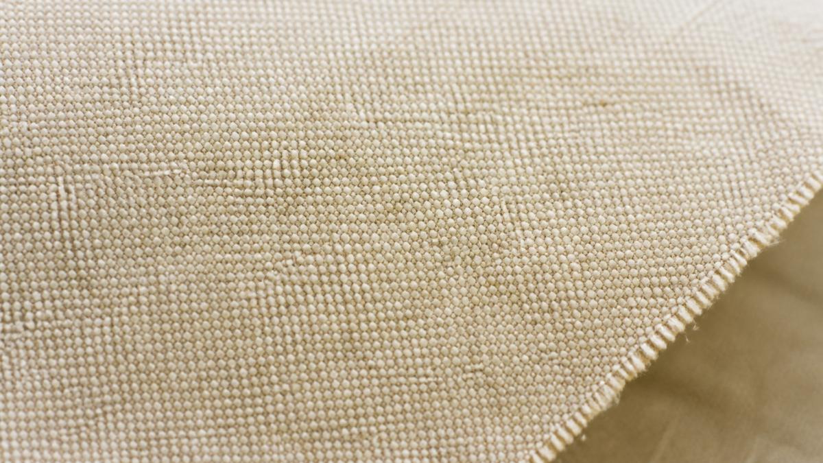 Close-up of quilting cotton fabric with tight weave texture showing interlocked threads and smooth surface under natural light, revealing the uniform plain weave pattern