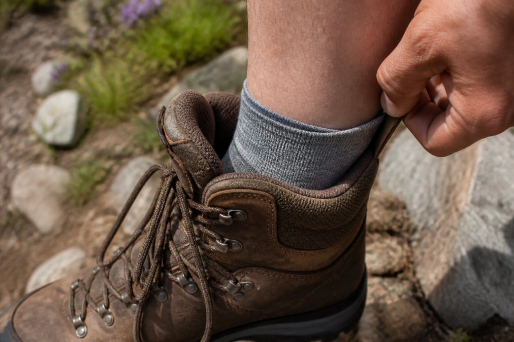 Close-up of a trail runner's foot inside a hiking boot with proper sock fit, showing secure heel positioning and moisture-wicking fabric visible at the ankle collar