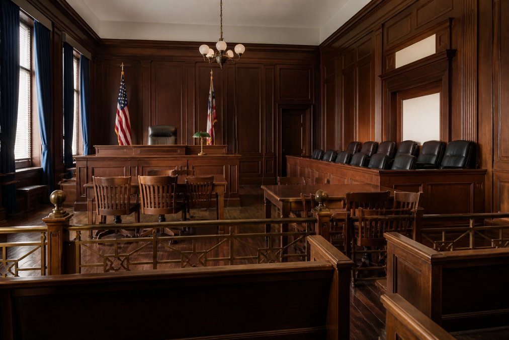 Formal courtroom interior showing judge's bench, jury box, and seating area, illustrating the formal trial environment and legal proceedings with natural courtroom lighting