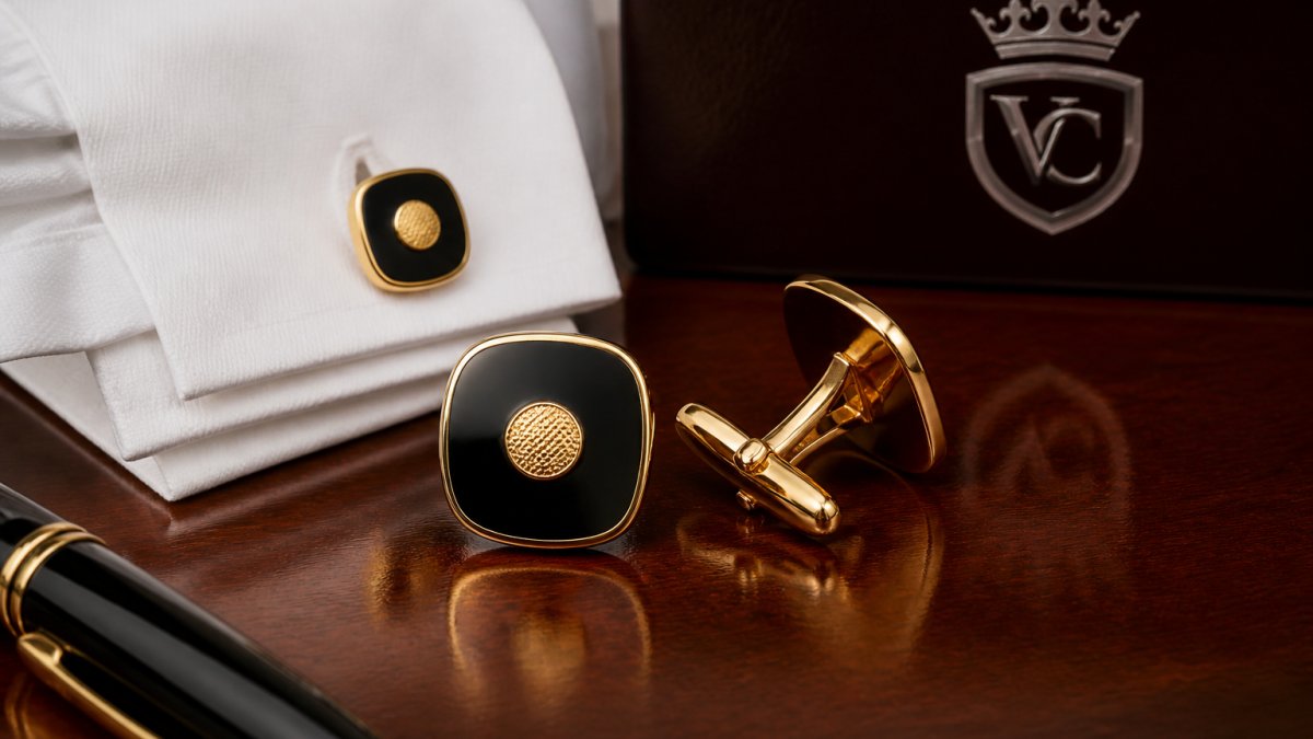 Close-up of luxury cufflinks displayed on polished mahogany surface with formal white dress shirt cuff and subtle gold plating reflections visible in professional lighting