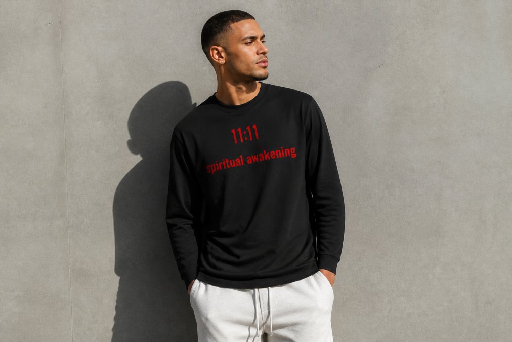 Person wearing a minimalist black oversized spiritual apparel shirt with celestial design, standing in natural sunlight against a neutral backdrop, showing the fit and design clarity