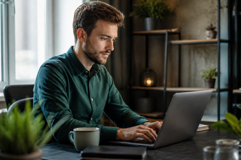 WordPress backups automatisch instellen: stap voor stap Professionele webmaster werkt aan WordPress dashboard op laptop in heldere kantooromgeving, koffiekopje naast het toetsenbord