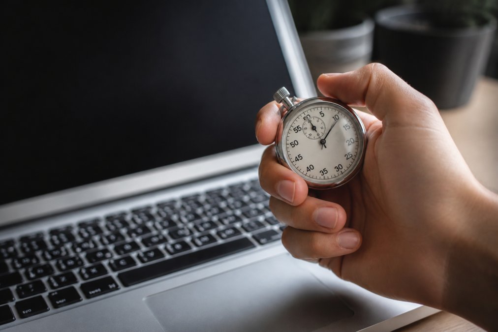 Geschäftsperson sitzt konzentriert an einem Schreibtisch und schaut auf einen Monitor mit Leistungskennzahlen und Hosting-Metriken, modernes Büro mit natürlichem Licht