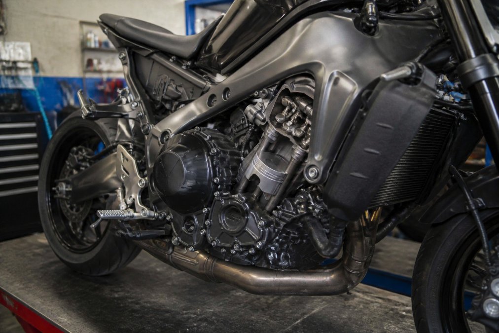 Close-up van de drie-cilinder CP3 motor van de Yamaha MT-09 in een technische werkplaats, met zichtbare cilinders, zuigers en chromen details onder helder werkingslicht