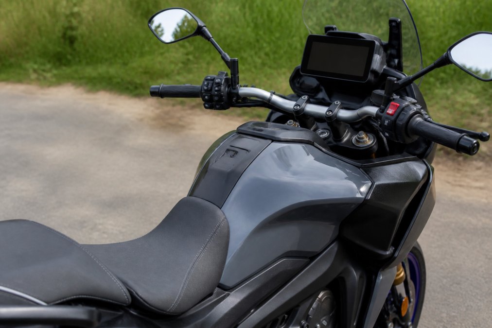 Close-up van de zitpositie en het stuur van een Yamaha Tracer 09, met duidelijk zicht op de ergonomische zitting, handvatten en TFT-display in daglicht
