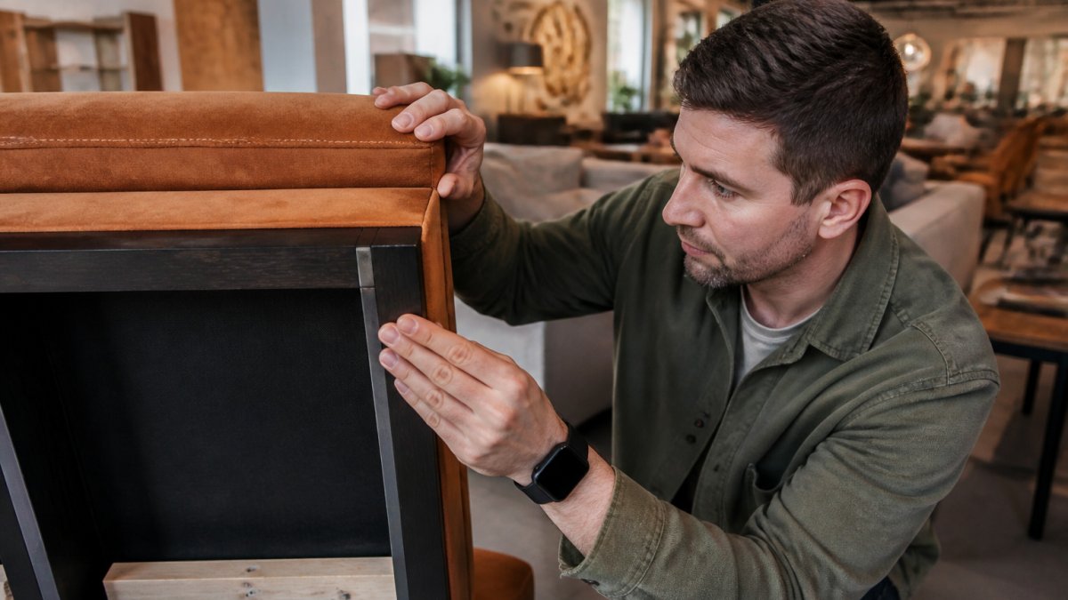 Iemand inspecteert zorgvuldig de houtverbindingen en afwerking van een meubel in een showroom.