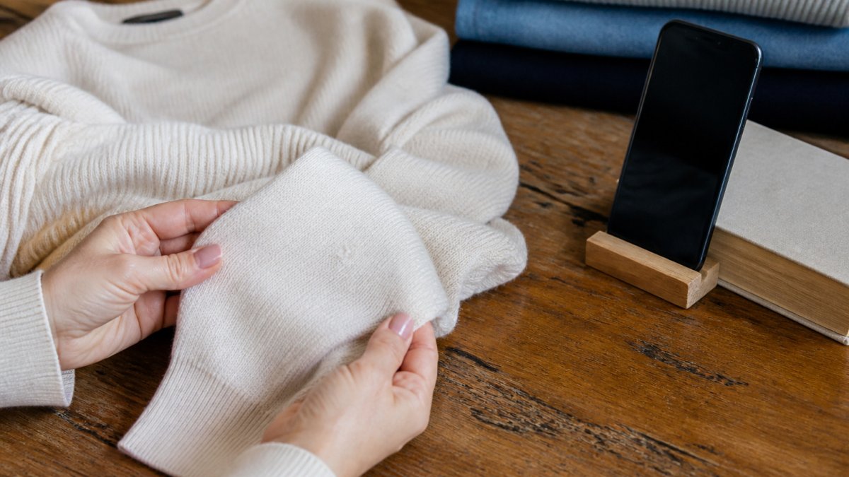Nahaufnahme beim Fotografieren eines hellen Strickpullovers mit sichtbarem Pilling für die Zustandsbeschreibung.
